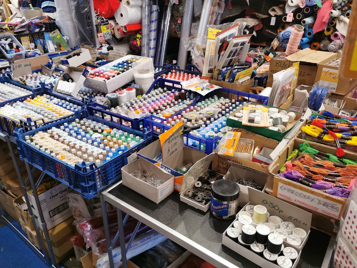 Trays of haberdashery at Z. Butt Textiles: bobbins, embroidery skeins, seam rippers, needles and sewing notions.