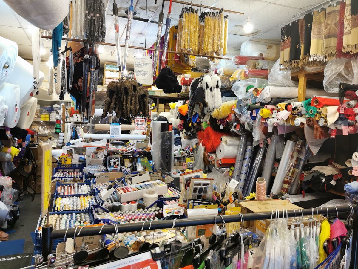 Inside Z. Butt Textiles on Brick Lane, floor-to-ceiling rolls of fabric and hanging embroidered shawls filling every wall.